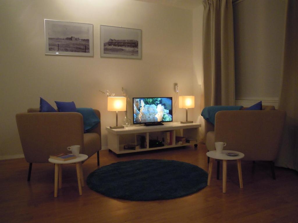 een woonkamer met 2 stoelen en een televisie bij Appartement Seabird in Zandvoort