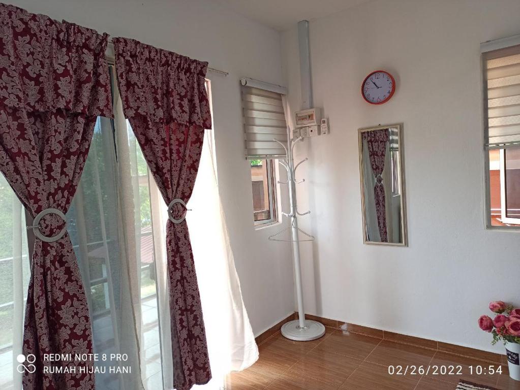 a room with a window with curtains and a clock at Teratak Yoi in Pantai Cenang