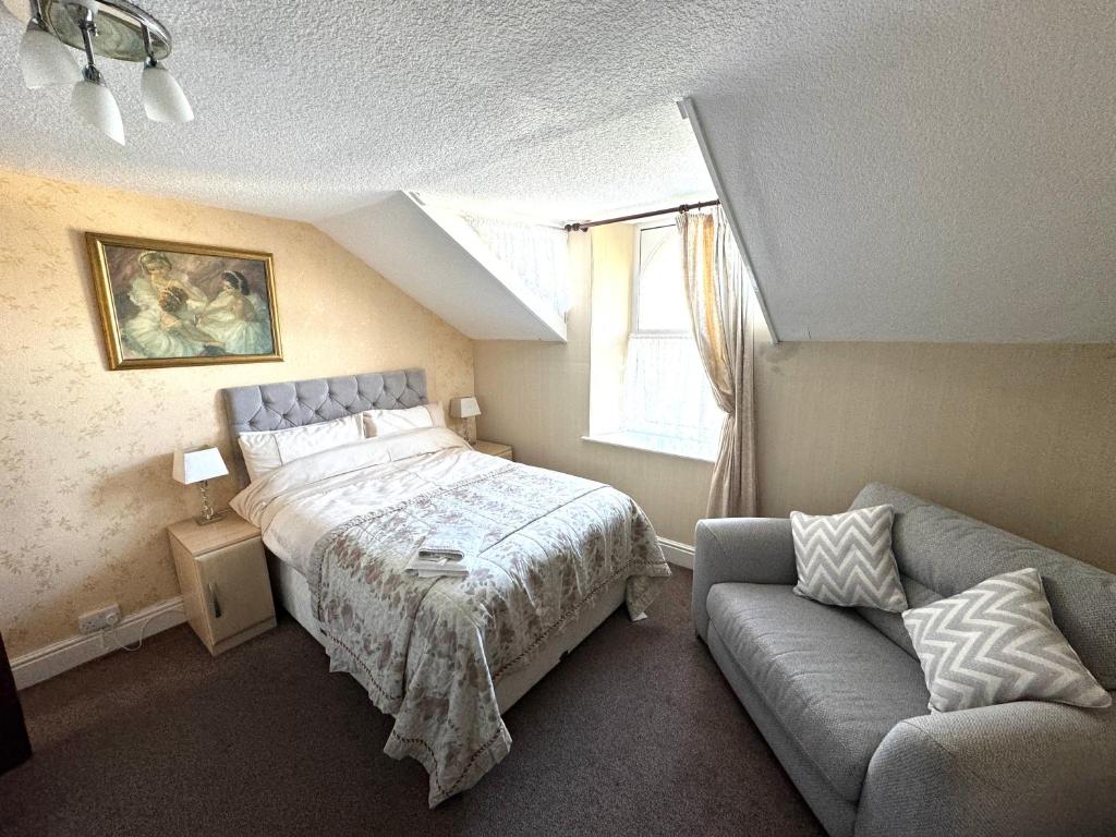 a bedroom with a bed and a couch and a window at Ashfield Guesthouse in Douglas