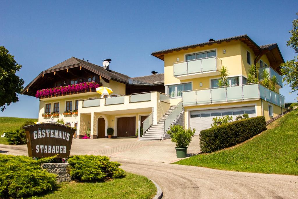 une grande maison jaune avec un panneau devant elle dans l'établissement Gästehaus Stabauer, à Mondsee