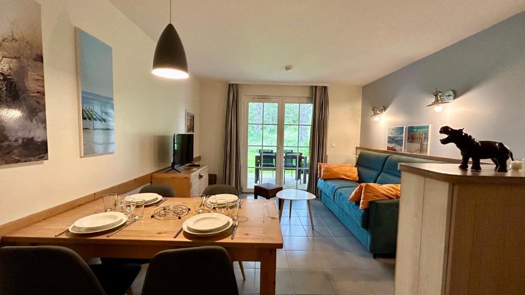 a living room with a table and a blue couch at Appartement avec terrasse vue sur le parc de golf in Fort-Mahon-Plage