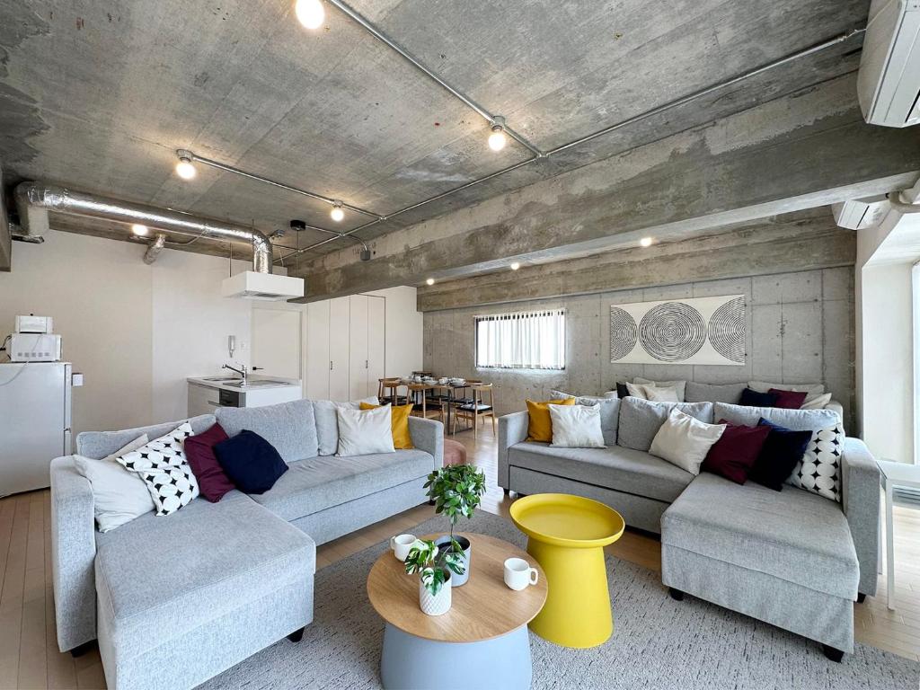 a living room with two couches and a table at b hotel M's lea - Modern Spacious Apartment Beside Peace Park 10 ppl in Hiroshima