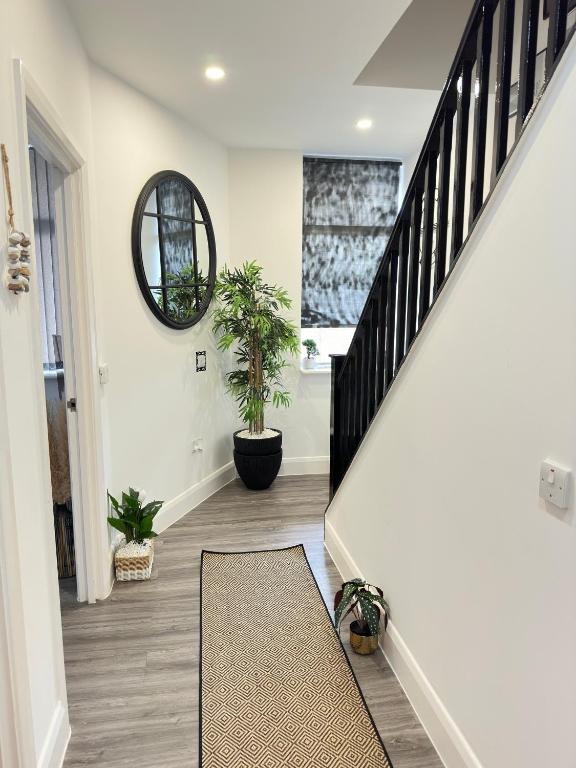 a hallway with stairs with potted plants and a mirror at JayGees luxury homes in Lower Gornal