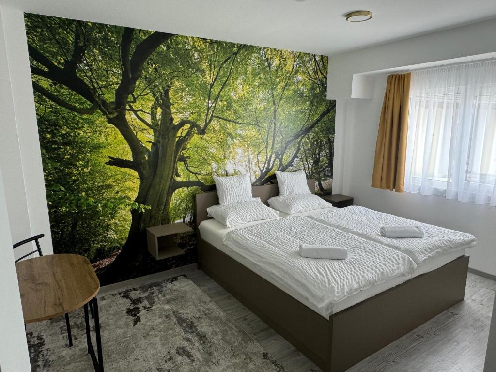 a bedroom with a large tree mural on the wall at Pótkerék Motel in Győr