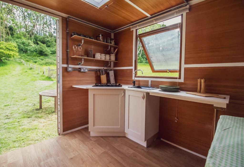 a kitchen in a tiny house with a window at Leto Shepherds Hut By Airpremier in Alfriston