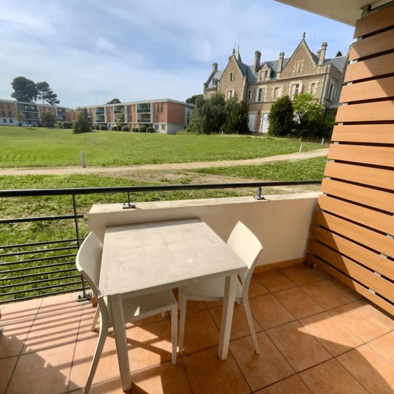 une table et une chaise sur un balcon avec vue sur un immeuble dans l'établissement Casa du sud, à Béziers