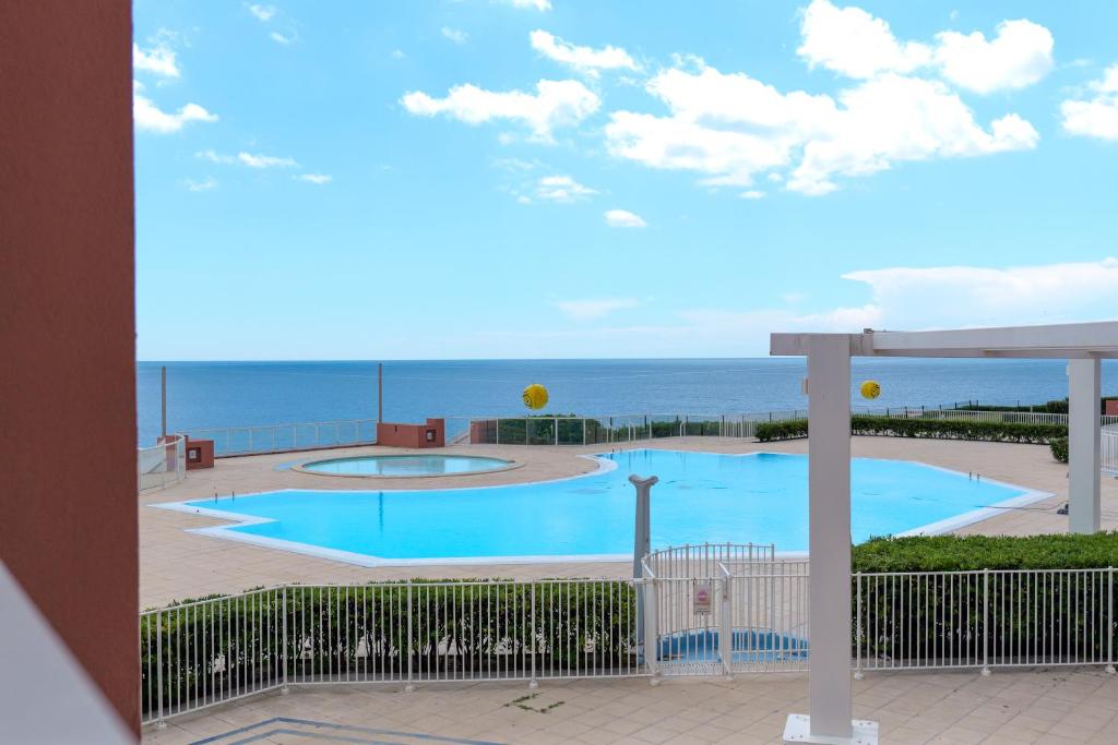 une piscine avec l'océan en arrière-plan dans l'établissement Appartement C 529 piscine front de mer, à Sète