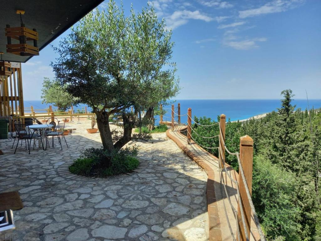 a wooden fence with a tree on a patio at Rahoni Park & Suites in Dhërmi