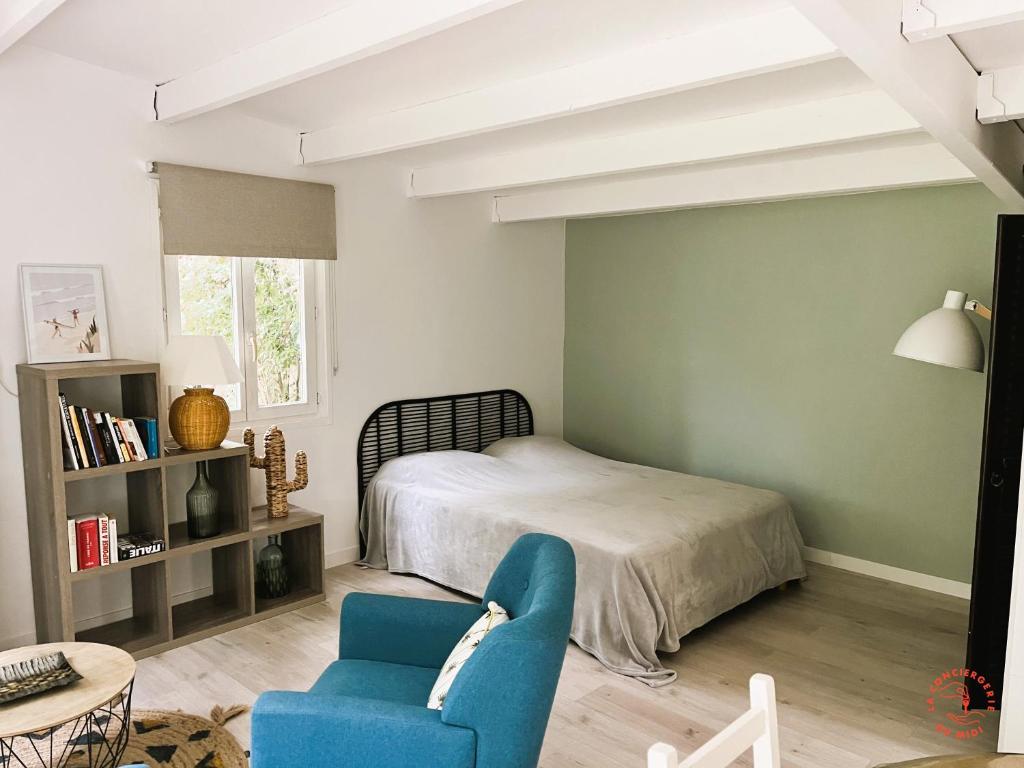 a bedroom with a bed and a blue chair at Gîte Studio Les Ecureuils in Narbonne