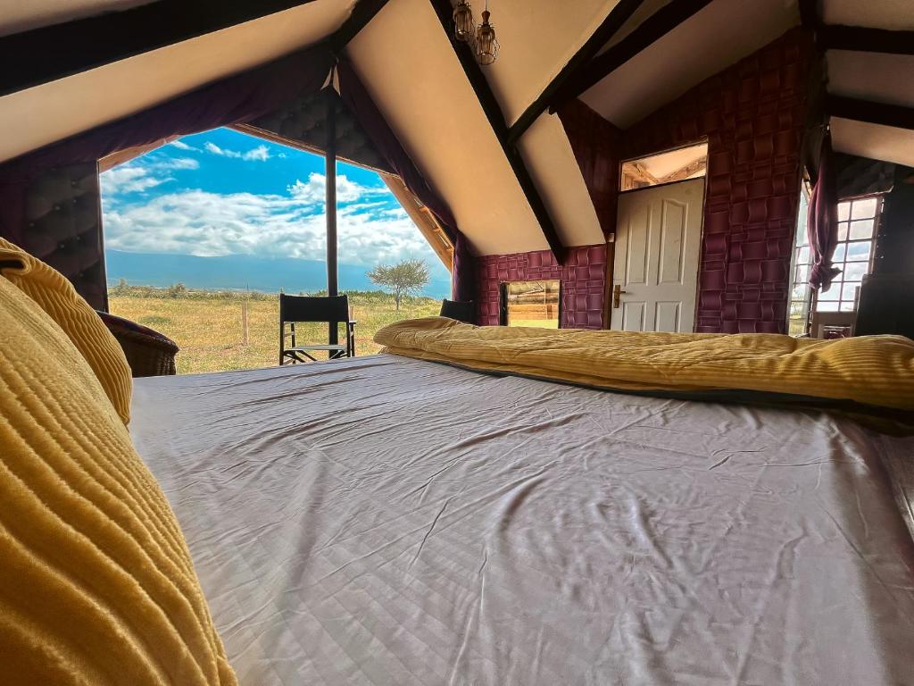 a bed in a room with a view of a field at Kilimanjaro view cabin-Amboseli in Oloitokitok 
