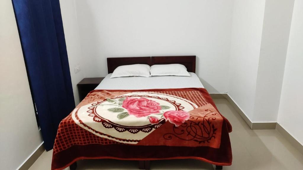 ein Bett mit einer Decke und zwei Rosen darauf in der Unterkunft Akbar Cottages in Anachal