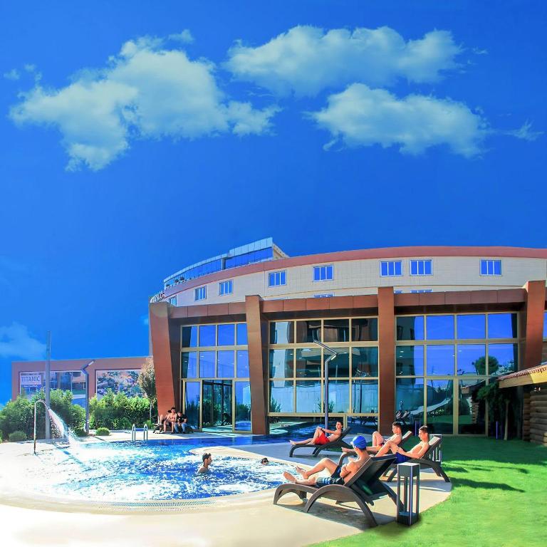 a group of people sitting in a pool in front of a building at Titanic Hotel & SPA in As Sulaymānīyah