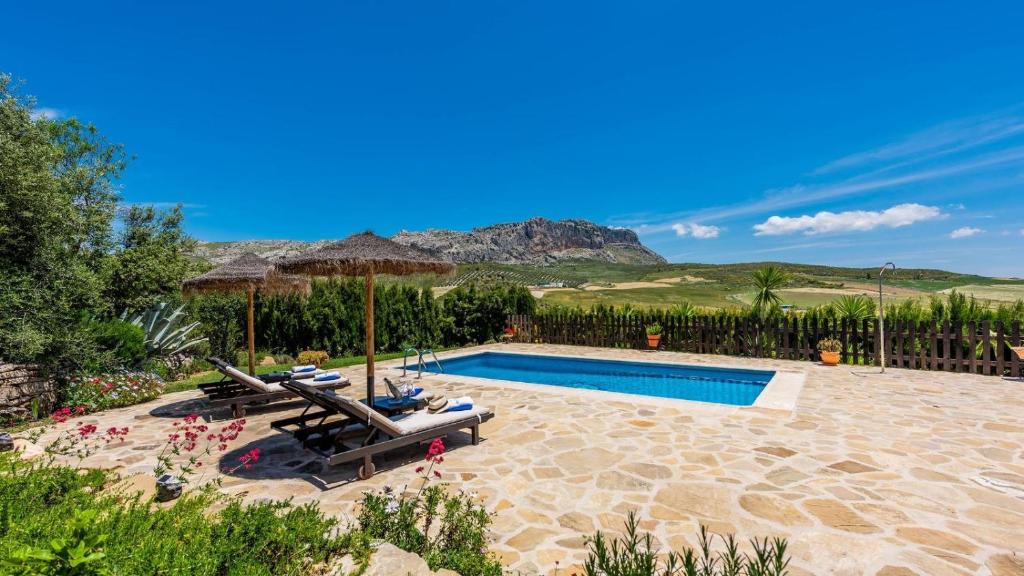 a swimming pool with chaise lounge chairs and an umbrella at Casa Tere Antequera - La Higuera by Ruralidays in Antequera