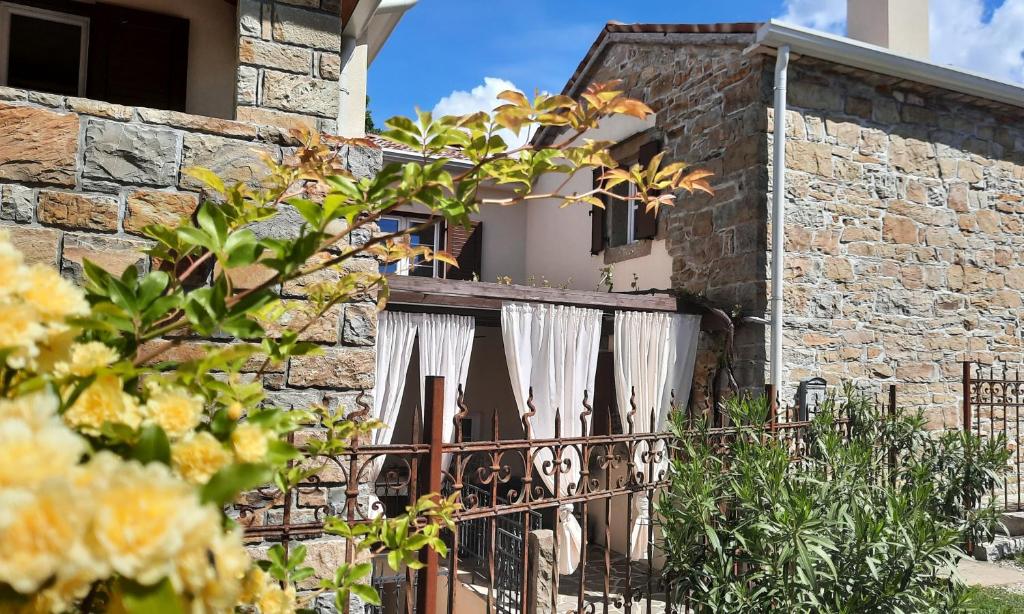 una casa in pietra con cancello e fiori di Guest house Nostalgia a Gračišče