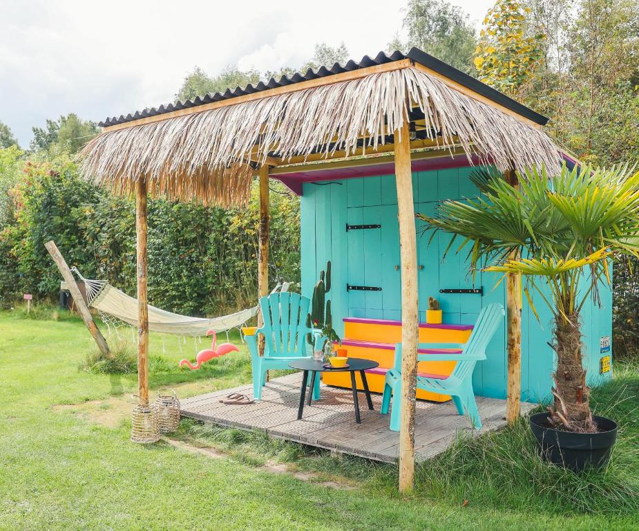 Cabaña azul con sillas, mesa y hamaca en Caribbean Bedstee voor 2 personen, en Paasloo