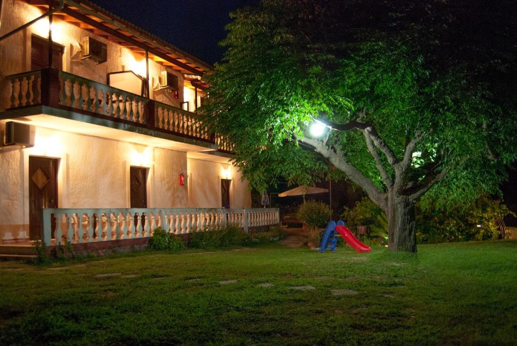 Corfu Country House في فيتالاذيس: منزل فيه شجره في الساحه ليلا