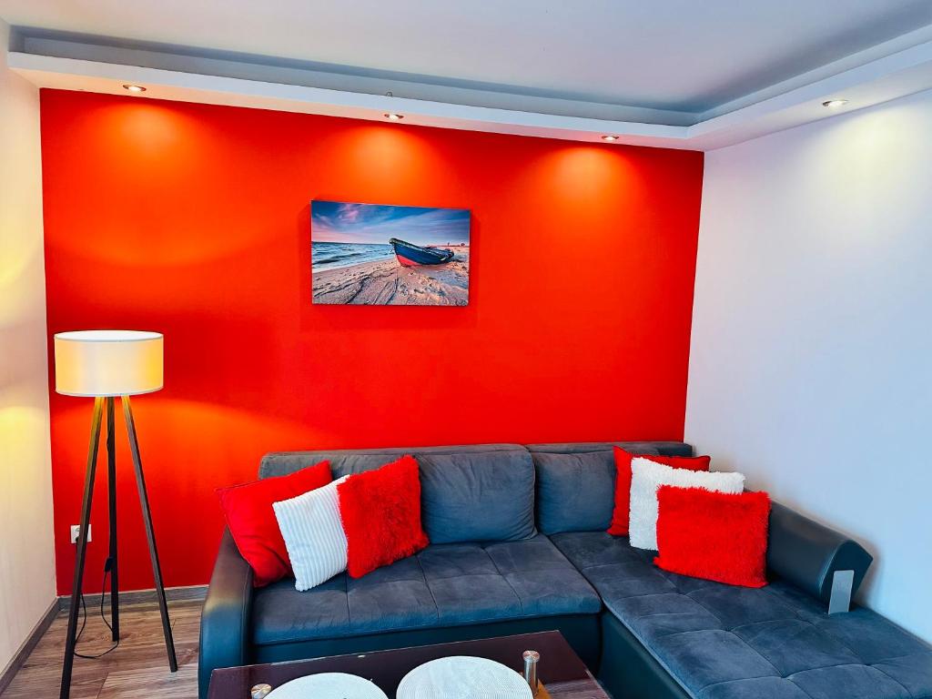 un soggiorno con divano contro una parete rossa di Apartamenty w Sercu Miasta a Puck