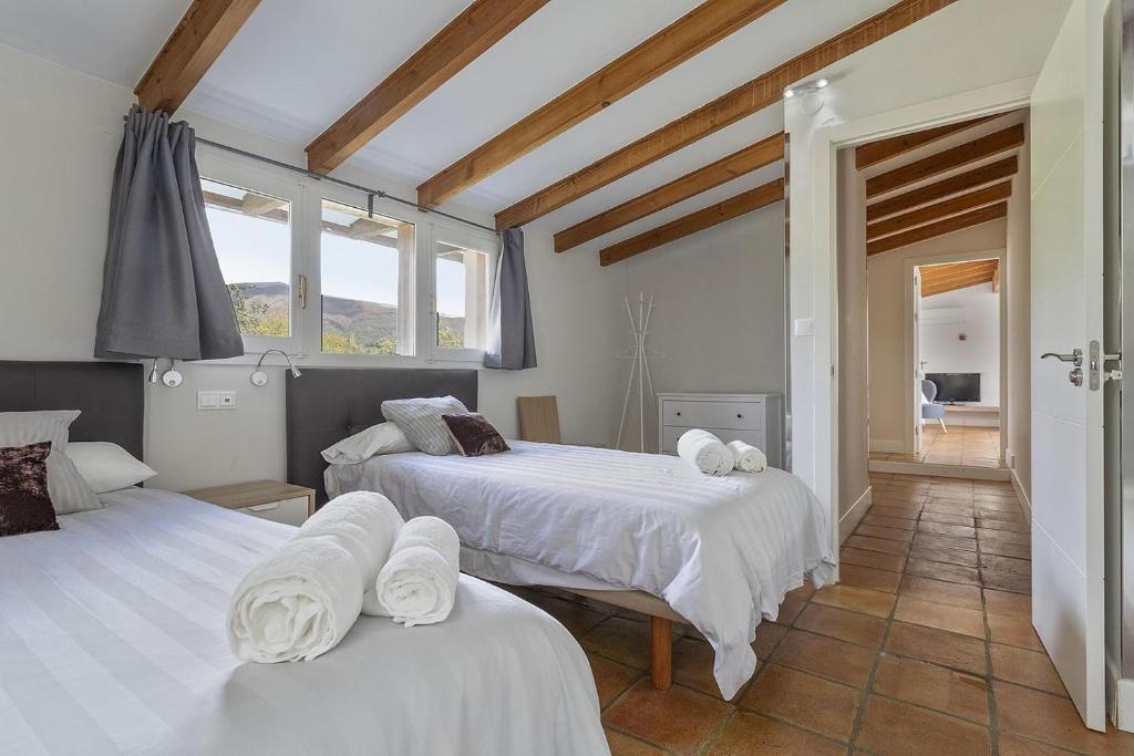 a bedroom with two beds with white sheets at Casa de lujo con piscina, pádel y BBQ in Candeleda