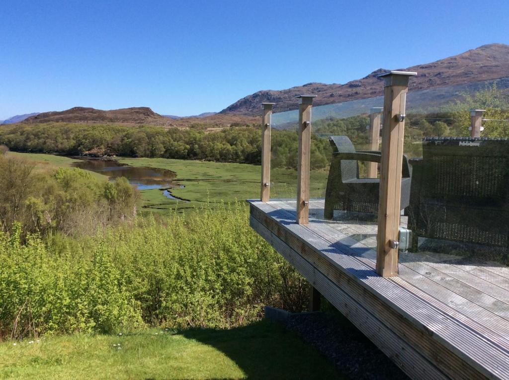 una terraza de madera con una silla encima en Maol View Apartment, en Kyleakin