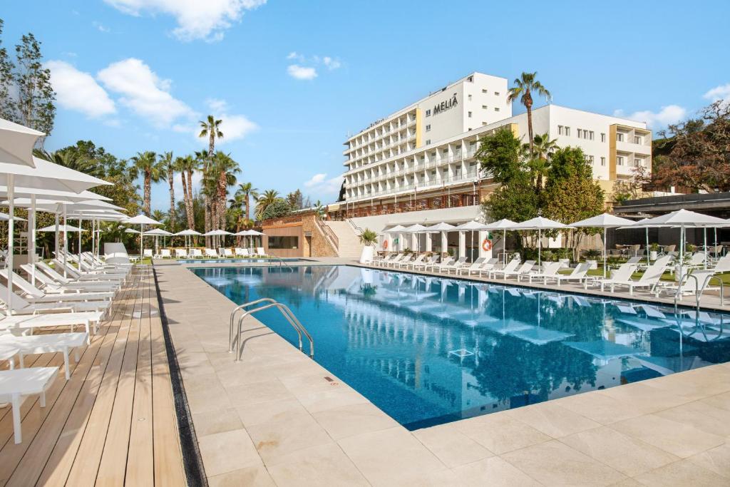 a pool at a hotel with chairs and umbrellas at Meliá Lloret de Mar in Lloret de Mar