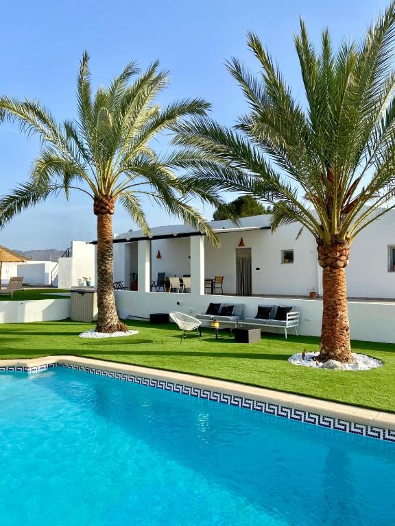 a villa with palm trees and a swimming pool at Villa Oasys in Almería