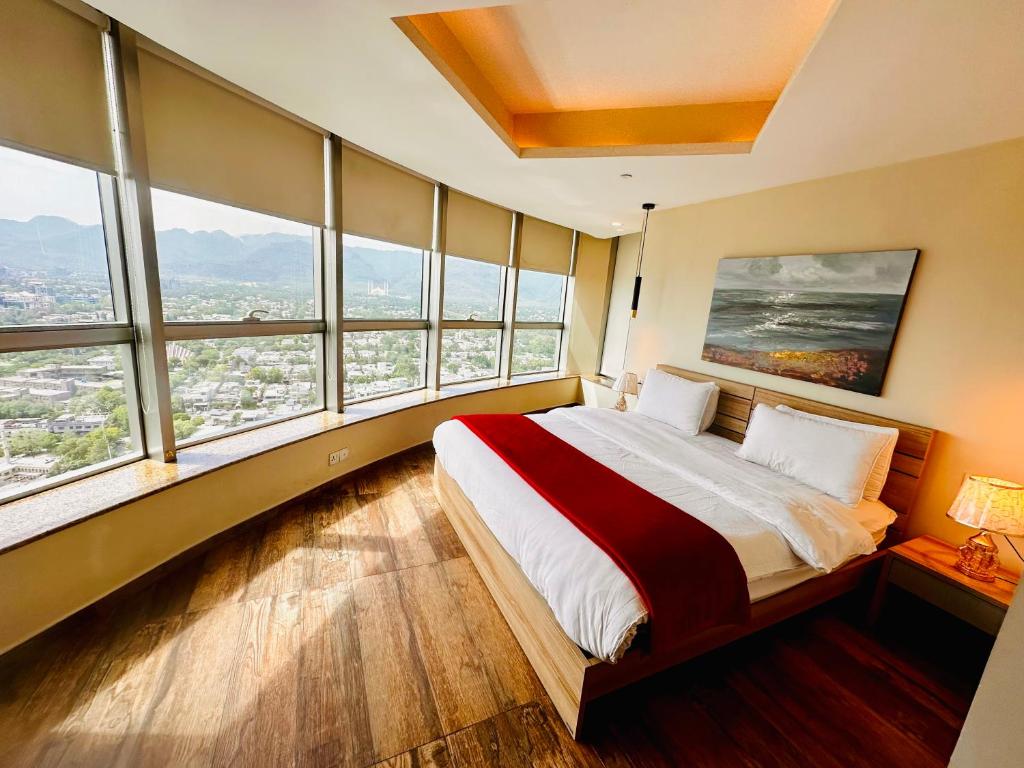 a bedroom with a large bed with large windows at Centaurus Apartment Three Bed in Islamabad
