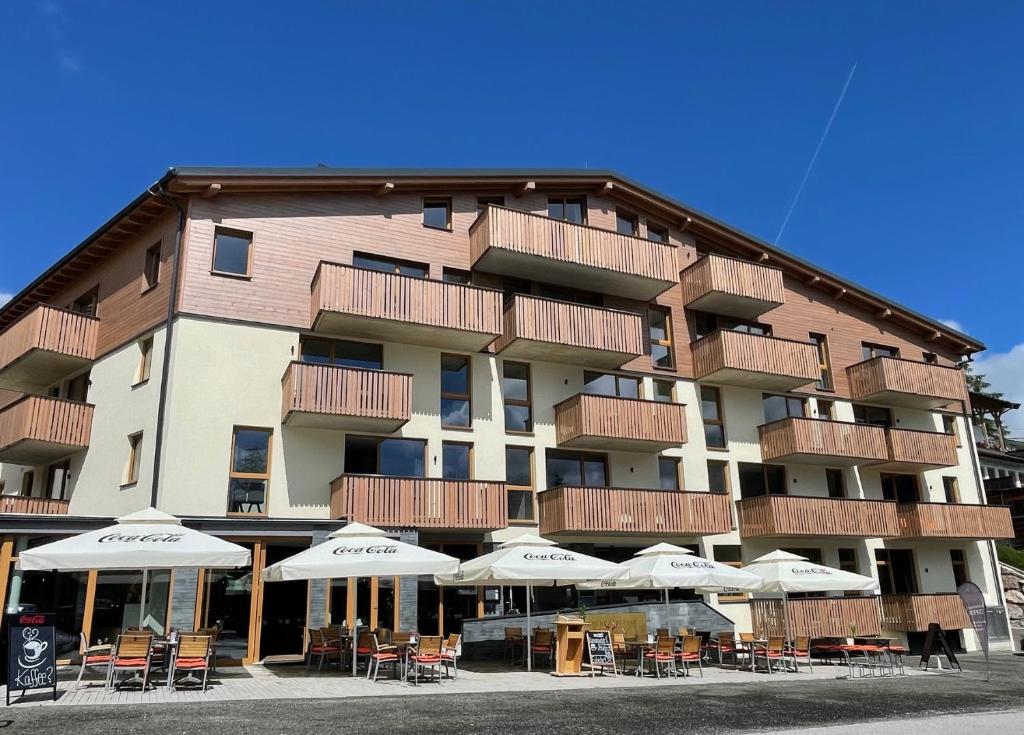 a building with tables and umbrellas in front of it at Alpenstyle Resort Fieberbrunn by AlpenTravel in Fieberbrunn