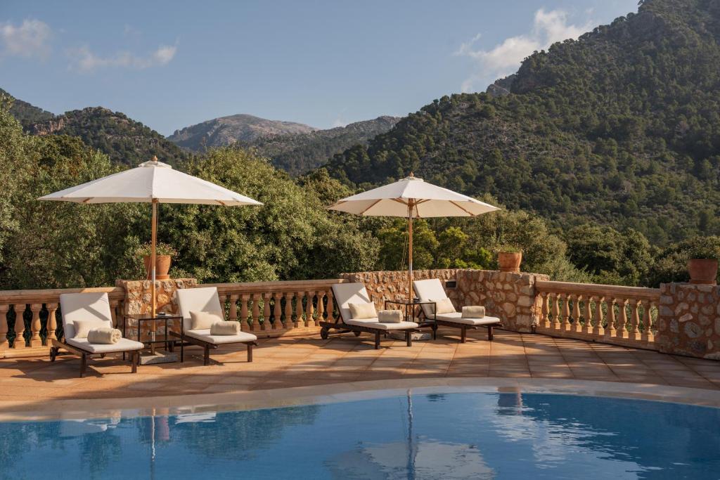 a patio with chairs and umbrellas and a pool at Finca Can Beneit in Binibona