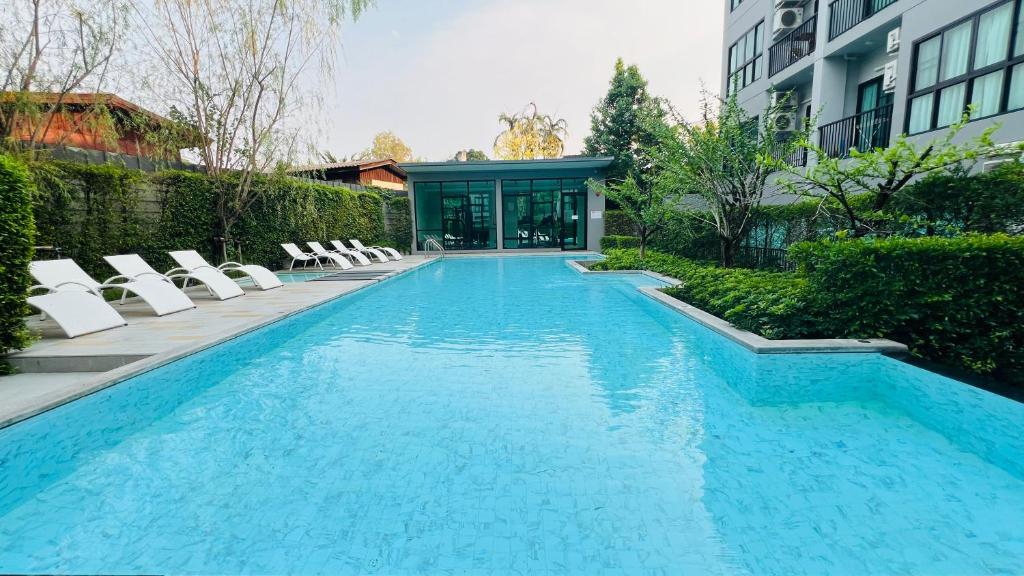チェンマイにあるNear nimman Maya swimming pool condo1BRの椅子と建物のあるプール