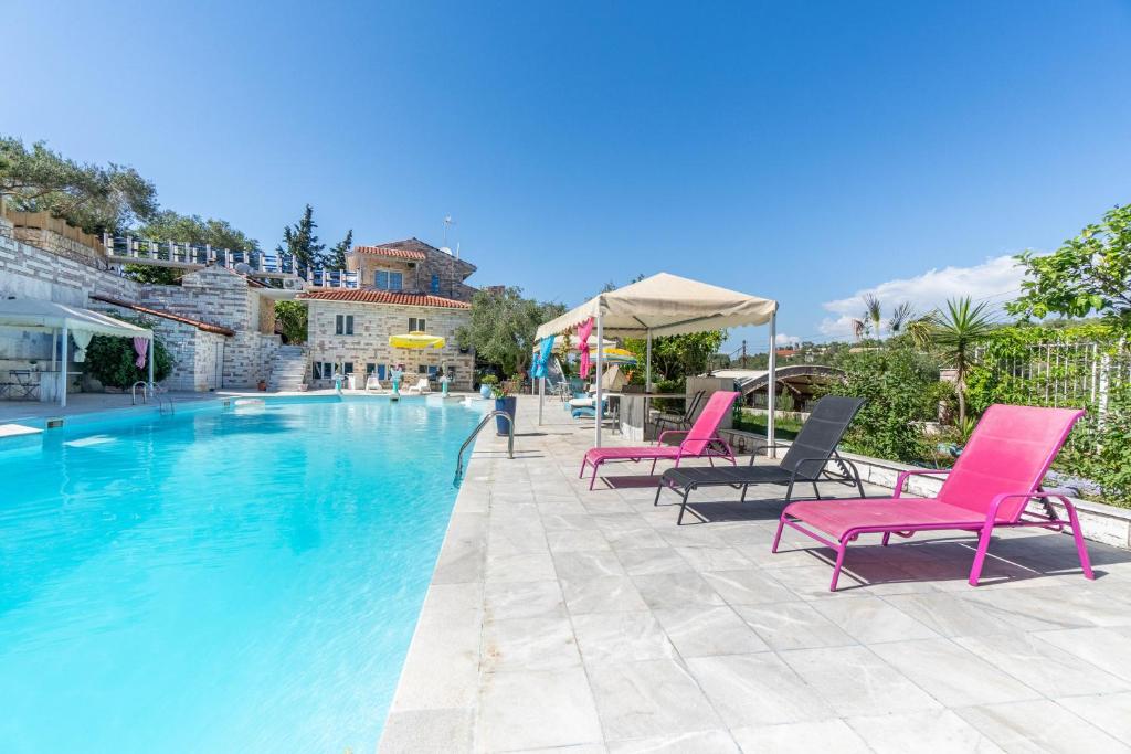 a large swimming pool with pink chairs and umbrellas at Paco's Superior Double Villa 15 in Oziás