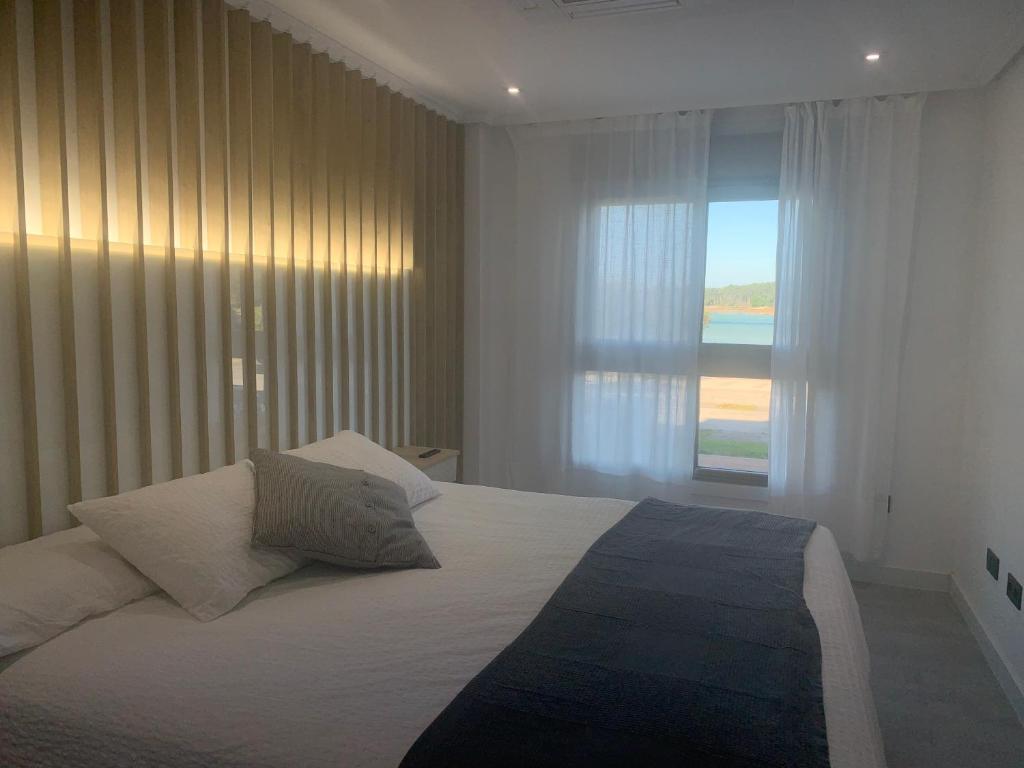 a bedroom with a large white bed with a window at El capricho de la ría in O Grove
