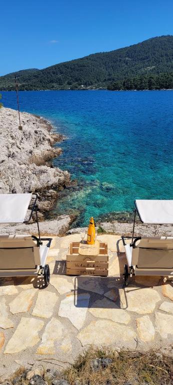 two beach chairs and a fire hydrant on a beach at PomaloVilla at Gradina Cove in Vela Luka
