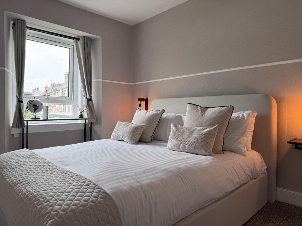 a bedroom with a white bed with a window at The Glendevon Hotel in Auchterarder