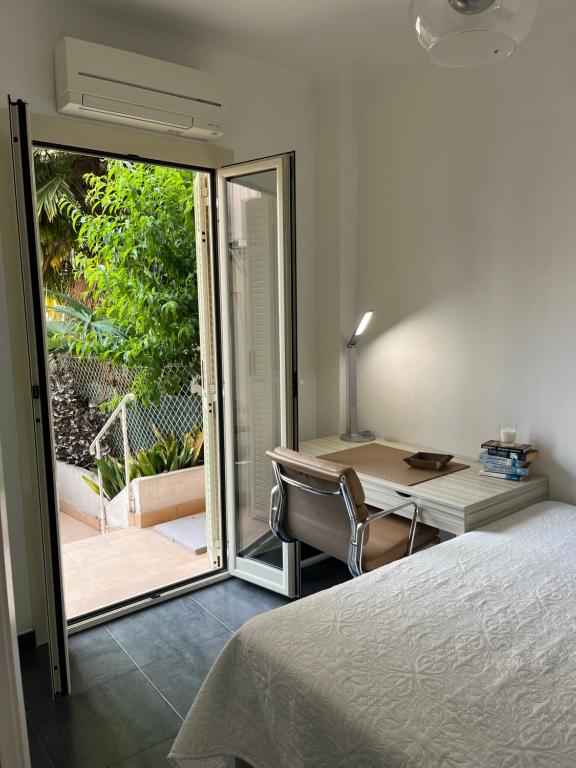 a bedroom with a bed and a desk and a sliding glass door at Perfectly located holiday place in Beaulieu-sur-Mer