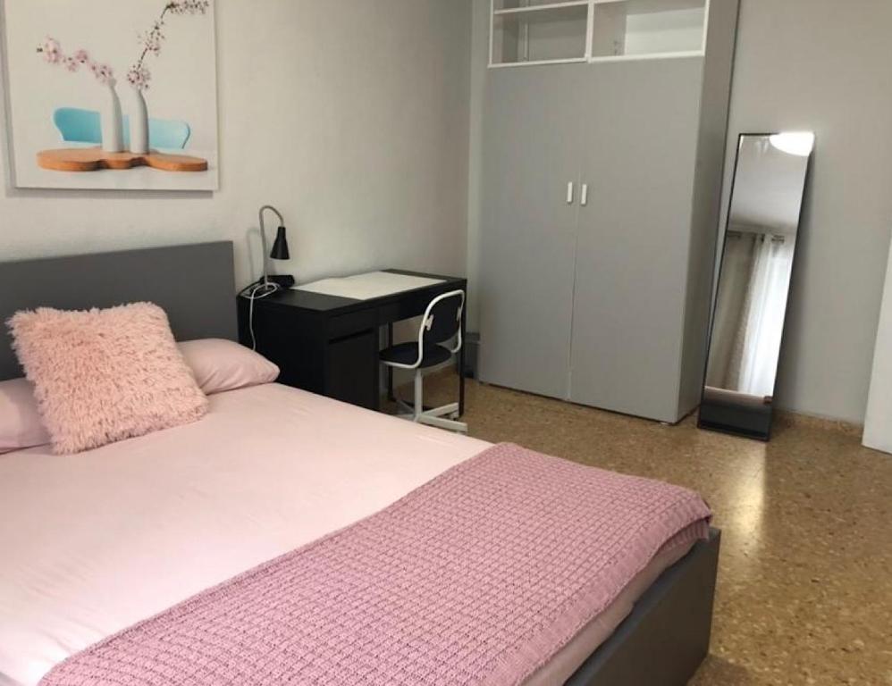 - une chambre avec un lit et un bureau avec une couverture rose dans l'établissement Rooms near the Beach Cabanyal and Universities, à Valence