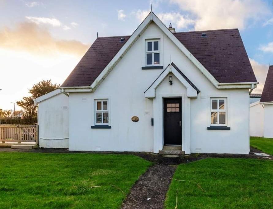 a white house with a black door in a yard at Sunny Cottage in Wexford