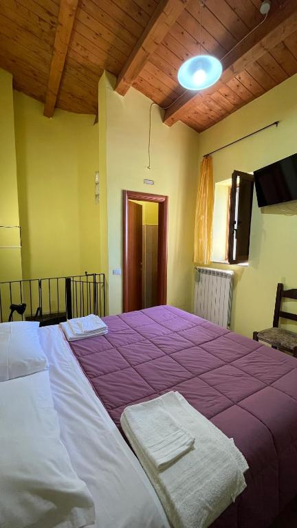 un grande letto in una stanza con una coperta viola di da sciuri case vacanza barisciano a Barisciano