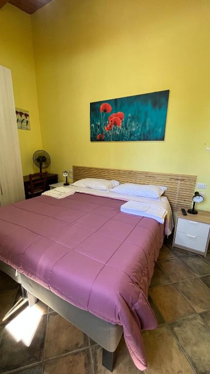un grande letto in una stanza con una coperta viola di da sciuri case vacanza barisciano a Barisciano