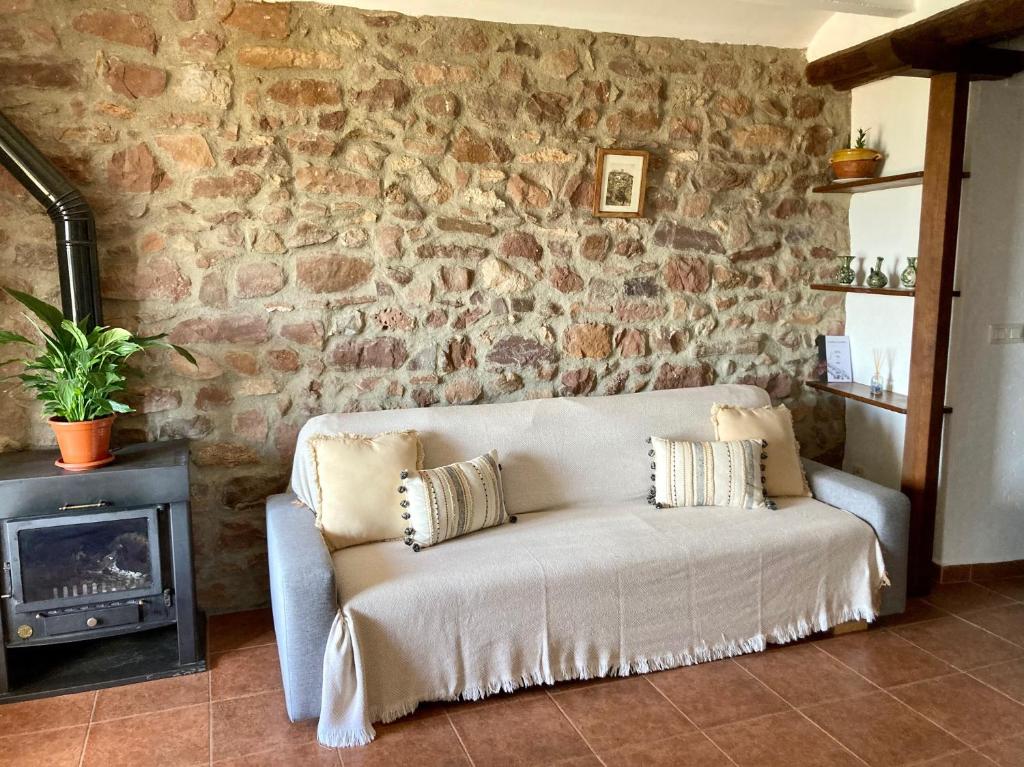 een bank in een woonkamer met een stenen muur bij El Portal de Vilafamés in Vilafames