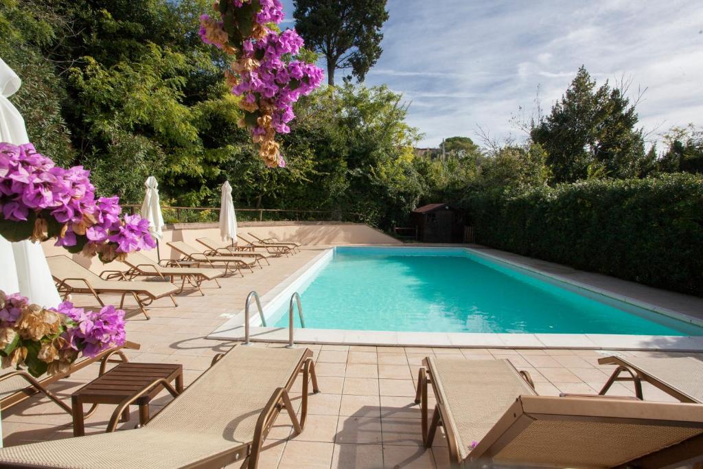 uma piscina com espreguiçadeiras e flores roxas em Garden Relais Le Fontanelle em Montescudaio