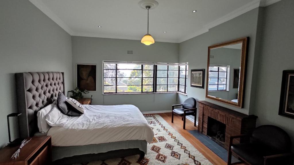 1 dormitorio con cama, espejo y chimenea en Southern Sky House, en Paarl