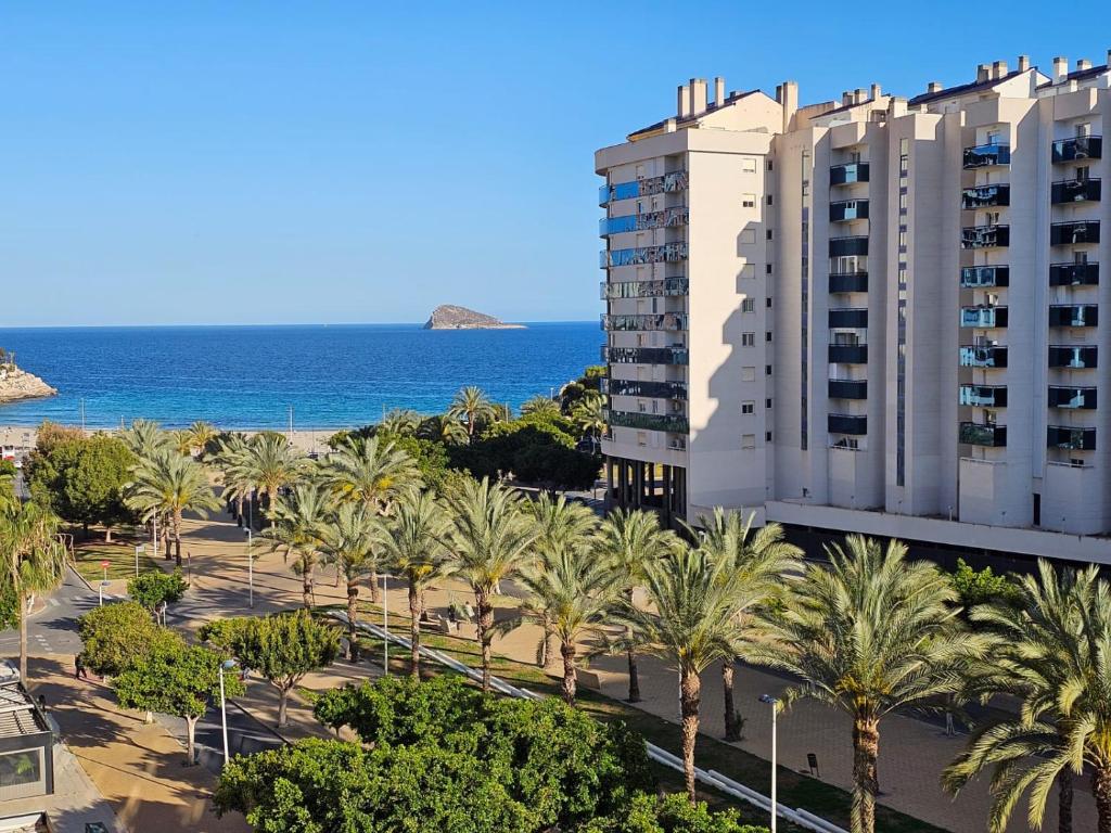 uma vista para um edifício e palmeiras e para o oceano em Apartamento El Gemelos em Cala de Finestrat