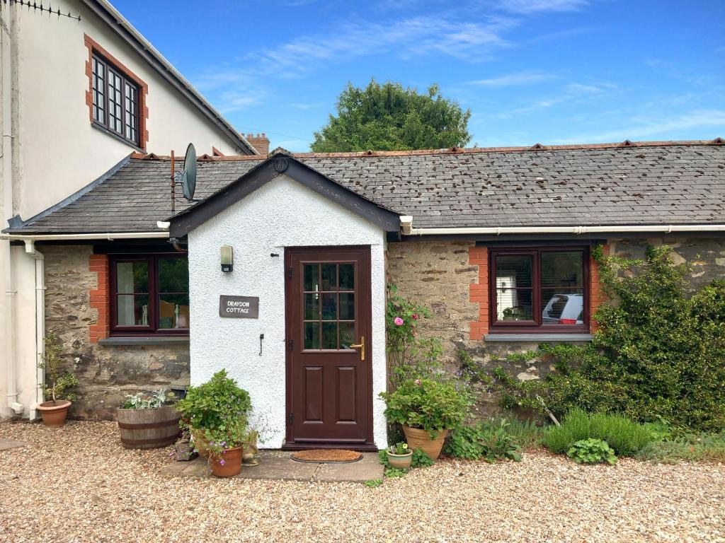 Cette petite maison en pierre est dotée d'une porte marron. dans l'établissement Draydon Cottage Dulverton, à Dulverton