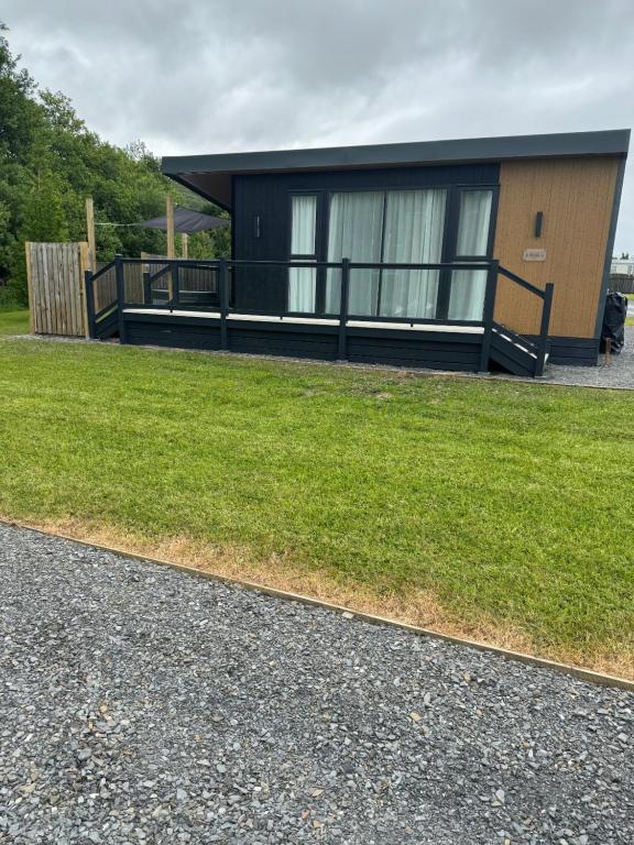 a small black house with a grass yard at luxury hot tub glamping apartment in Ireleth