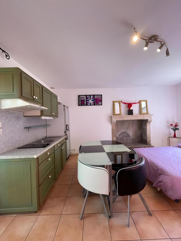 - une cuisine avec des placards verts, une table et un lit dans l'établissement Le Paloma - Bougeance - 7pers - Rêve Au Mans, à Saint-Pavace