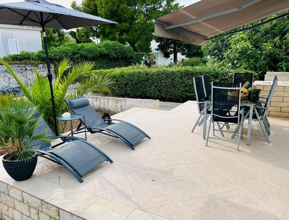 a patio with a table and chairs and an umbrella at House MARIJA in Novalja