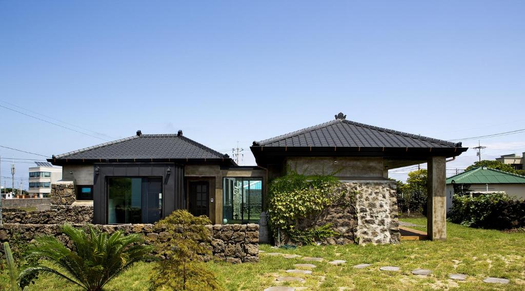 una pequeña casa en un patio con una pared de piedra en Casa Bonbon en Jeju