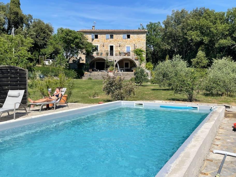 une femme assise sur une chaise à côté d'une piscine dans l'établissement Petit havre de paix en pleine nature cévenole, à Monoblet