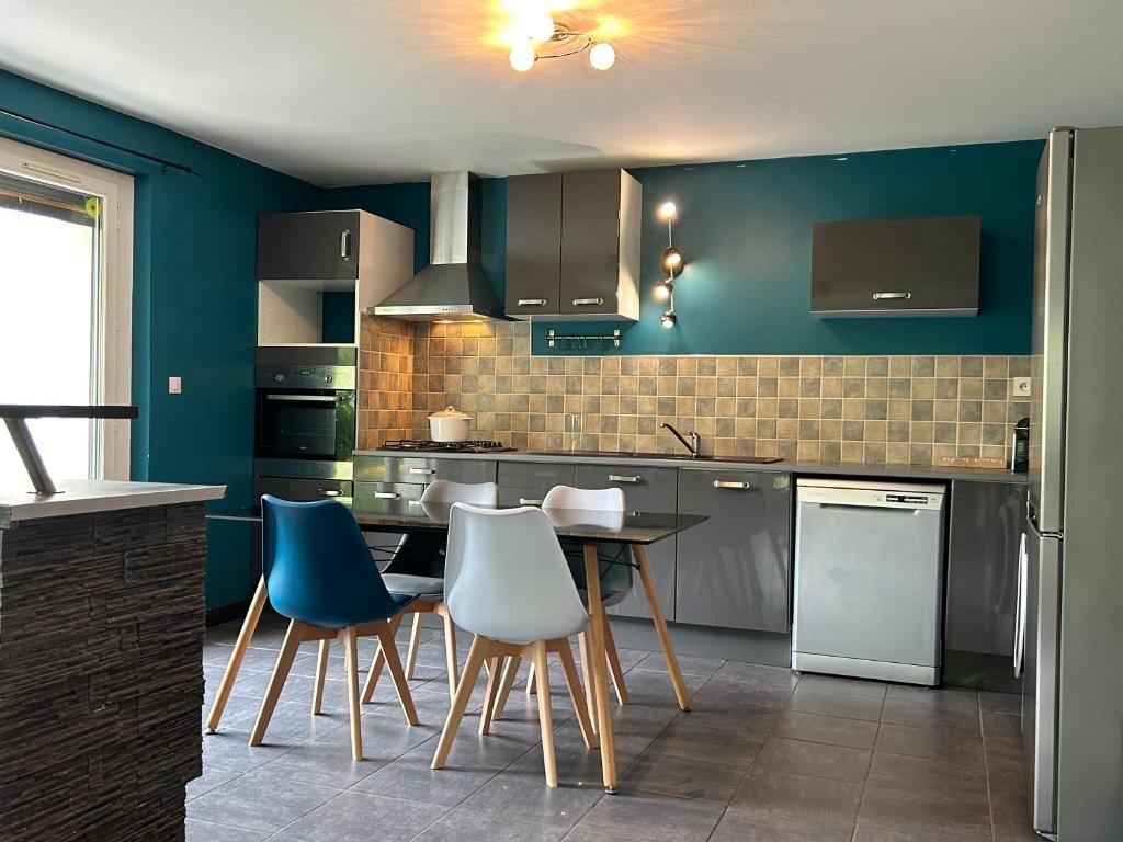 une cuisine avec des murs bleus et une table et des chaises dans l'établissement Écrin des Iris, au Bourg-dʼOisans