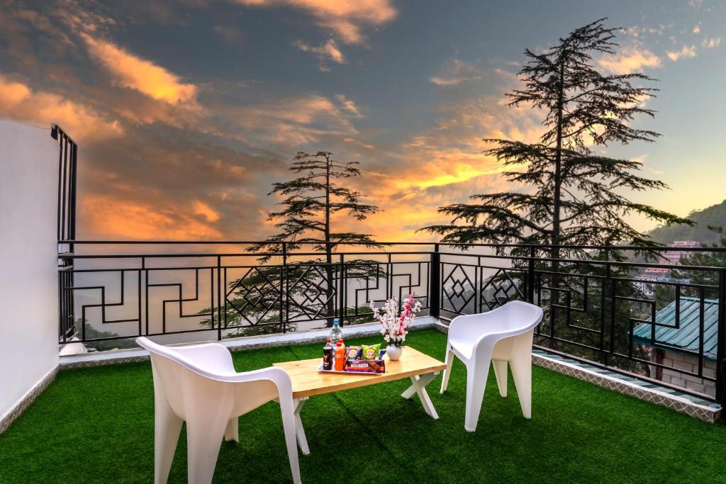 einen Tisch und Stühle auf einem Balkon mit Blick auf den Sonnenuntergang in der Unterkunft The Sunset Abode 4BR With Valley Views in Shimla